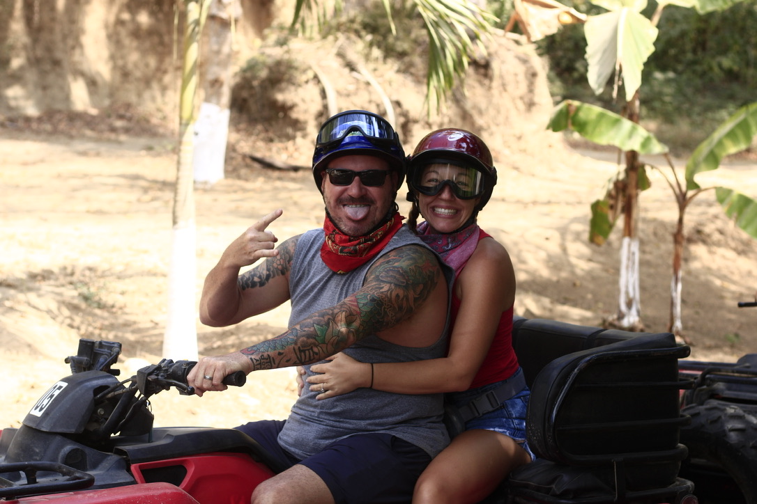 A couple riding an ATV in helmets