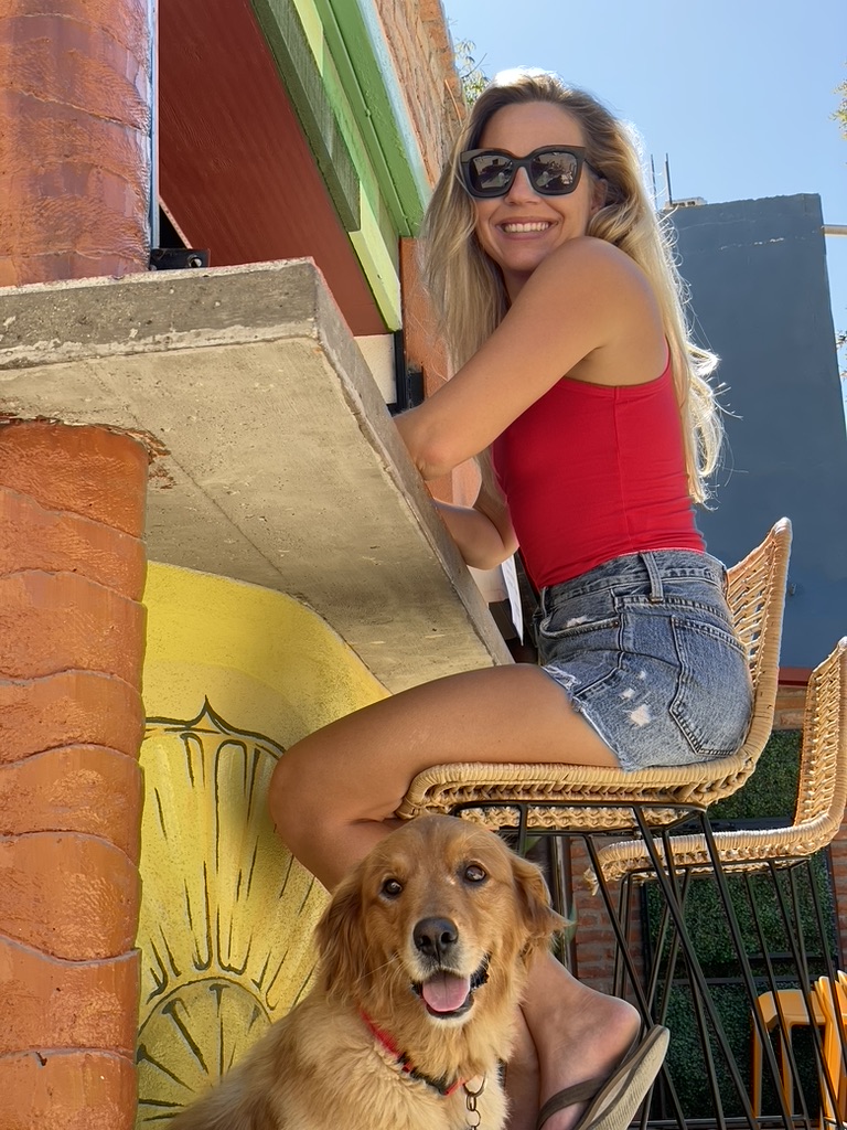 A woman at a bar with a golden retriever