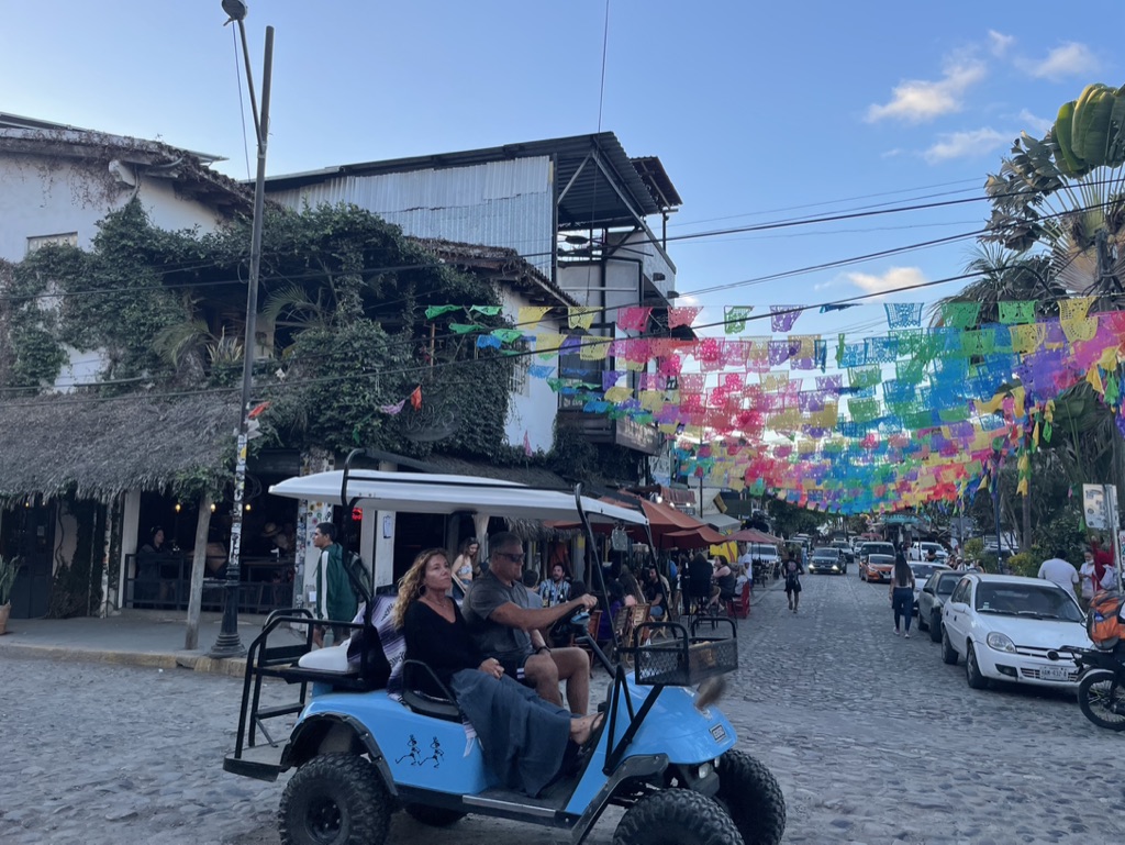 A golf cart on a Sayulita street under papel picado