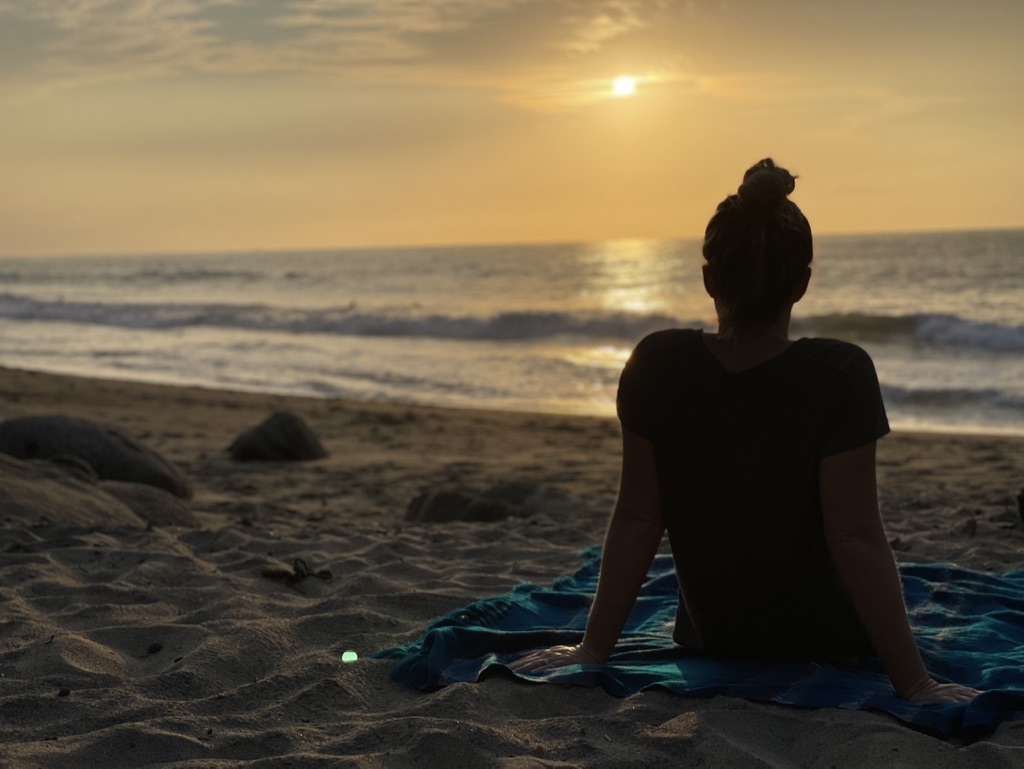 A woman on a blanket watching the sunset