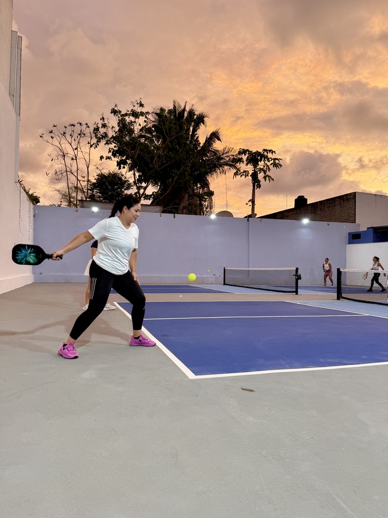 Woman hitting a forehand under a golden sunset