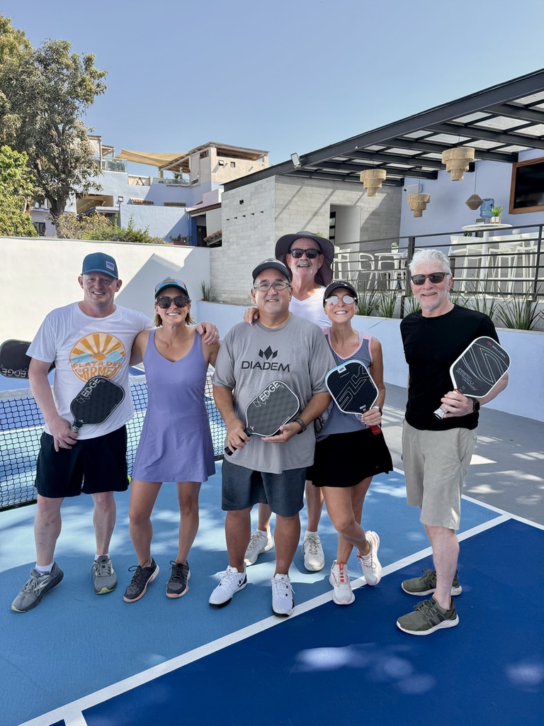 Group of six retreat guests smiling with their paddles