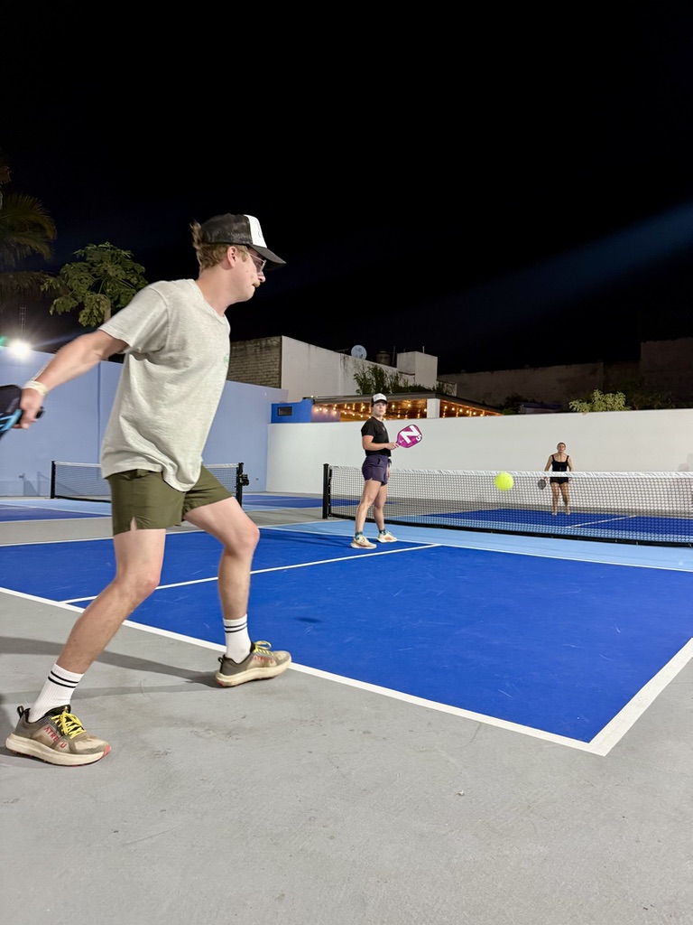 Man hitting a forehand under the court lights at night