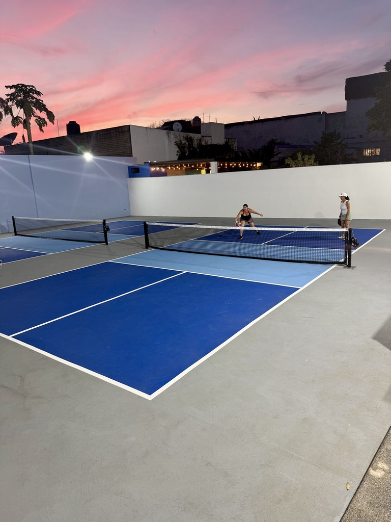 Wide view of the Nawalli courts under a pink sunset, mid-rally