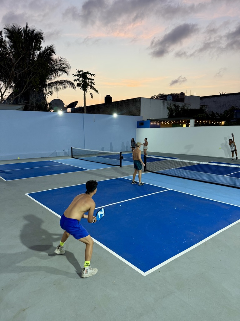 Sunset over multiple courts with a ready-position player in the foreground